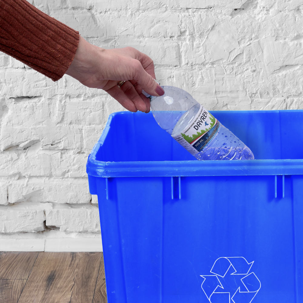 plastic bottle being emptied into blue recycling bin
