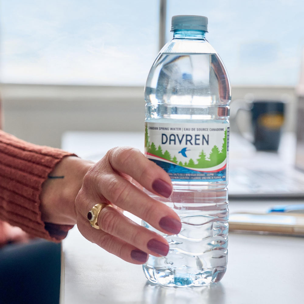 Womans hand holding a Water Bottle at desk 